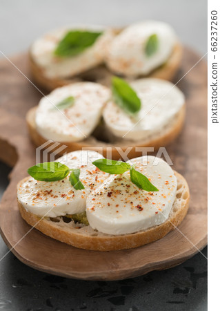 Bruschetta with mozzarella, basil and pesto on olive wood board Bruschetta with mozzarella, basil and pesto on olive wood board 66237260