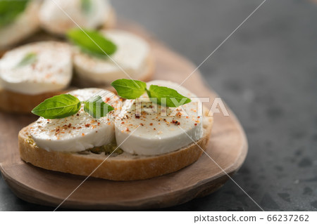 Bruschetta with mozzarella, basil and pesto on olive wood board 66237262