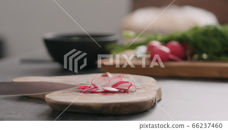 man slicing fresh radish on olive board side view man slicing fresh radish on olive board side view 66237460