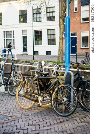 Cityscape of Delft, Netherlands: Bicycles and brick buildings on the side of a canal at sunset 66237506
