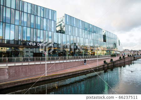 A station in Delft, the Netherlands with a glass building standing by the canal 66237511