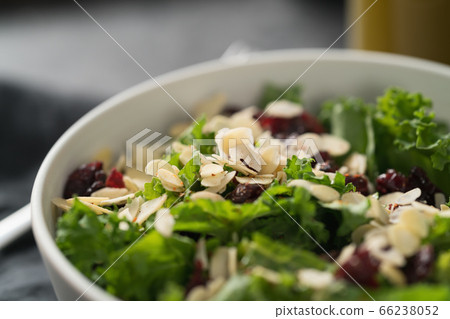 Salad with kale, cranberries and almond flakes in white bowl closeup 66238052