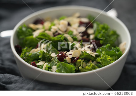 Salad with kale, cranberries and almond flakes in white bowl on linen napkin Salad with kale, cranberries and almond flakes in white bowl on linen napkin 66238068