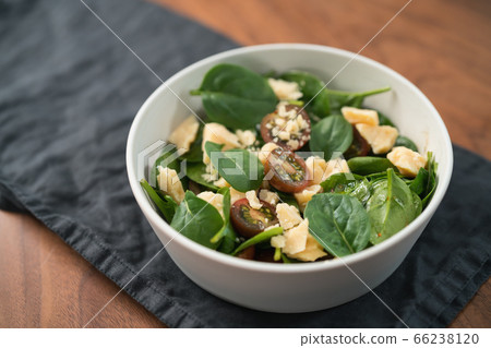 Salad with spinach, kumato tomatoes and cheese in white bowl on linen napkin 66238120