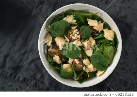 Salad with spinach, kumato tomatoes and cheese in white bowl on linen napkin 66238128