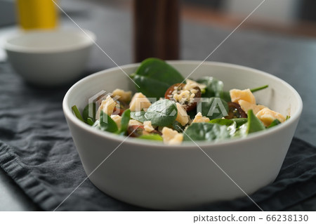 Salad with spinach, kumato tomatoes and cheese in white bowl on linen napkin 66238130