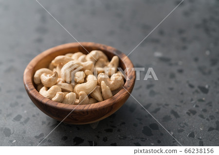 Dry cashew nuts in wood olive bowl on concrete background with copy space Dry cashew nuts in wood olive bowl on concrete background with copy space 66238156