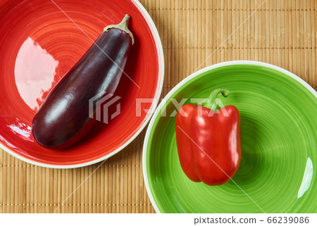 purple eggplant on a red plate and red bell pepper purple eggplant on a red plate and red bell pepper 66239086