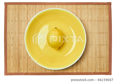 bright yellow lemon on a yellow plate on a cane 66239087