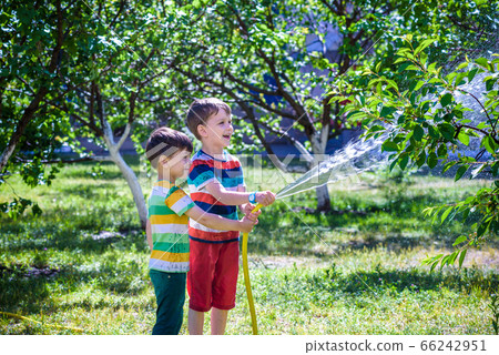 Brothers having fun splash each other with water 66242951