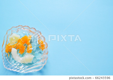 A mixed jelly of pineapple and mandarin orange in a glass plate like a shell on the lower left of the blue background [Top view] 66243596