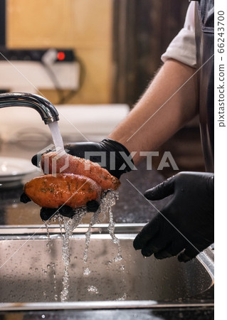 Washing sweet potatoes in sink 66243700