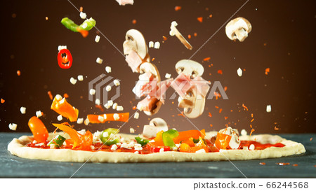 Falling raw ingredients on pizza 66244568