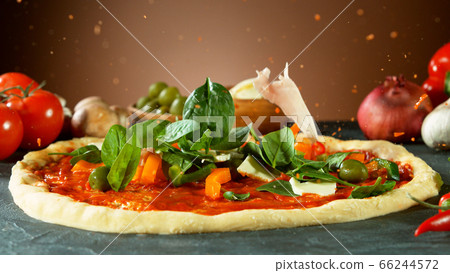 Falling raw ingredients on pizza 66244572