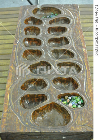 Traditional Mancala boardgame or congkak in Malay with glass pieces on wooden table. Traditional Mancala boardgame or congkak in Malay with glass pieces on wooden table. 66244671