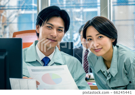 Male and female businessmen in work clothes working in the office while looking at materials Male and female businessmen in work clothes working in the office while looking at materials 66245441