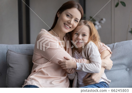 Portrait of happy mom and daughter hugging on couch 66245803