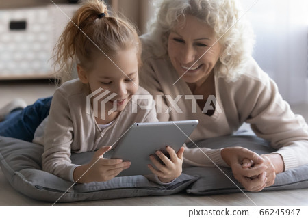 Happy little girl have fun using tablet with grandmother Happy little girl have fun using tablet with grandmother 66245947