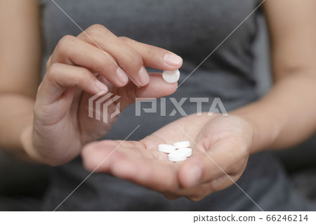 Close up of working woman taking in pill she is pours the pills out of the bottle,taking painkiller to reduce sharp ache concept,health care and medicine concept. Close up of working woman taking in pill she is pours the pills out of the bottle,taking painkiller to reduce sharp ache concept,health care and medicine concept. 66246214
