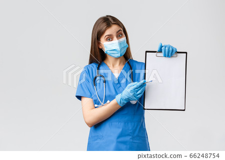 Covid-19, preventing virus, health, healthcare workers and quarantine concept. Friendly female nurse or doctor in blue scrubs and medical mask, explain info on clipboard, pointing paper 66248754