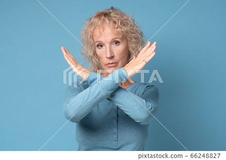 Serious mature woman showing stop gesture with crossed hands 66248827