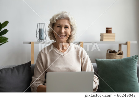 Portrait of smiling mature woman working on laptop at home Portrait of smiling mature woman working on laptop at home 66249042