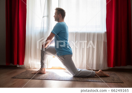 caucasian man in Anjaneyasana one leg lunge pose practicing online at home. 66249165