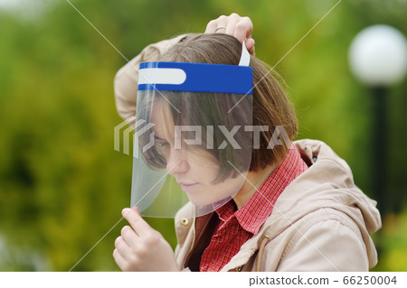 Young woman putting on face shield on street of 66250004