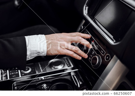 Businessman changing radio station while driving automobile Businessman changing radio station while driving automobile 66250607