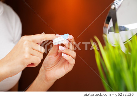 Woman removes contact lenses from a container with liquid 66252126
