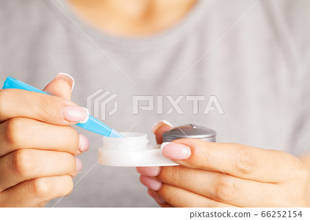 Woman removes contact lenses from a container with liquid Woman removes contact lenses from a container with liquid 66252154