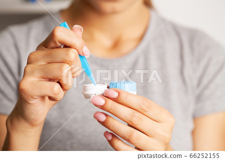 Woman removes contact lenses from a container with liquid Woman removes contact lenses from a container with liquid 66252155