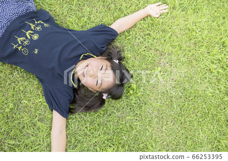 Elementary school girl lying on the grass 66253395