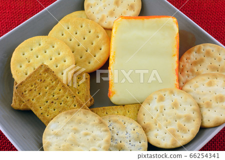 Close up of wedge of Port Salut semi-soft cheese on plate with assorted crackers 66254341