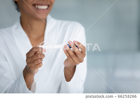 Close up smiling African American woman holding pregnancy test 66258266
