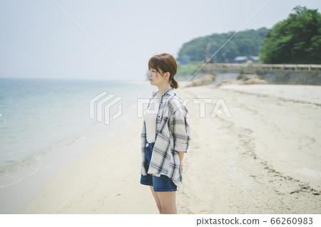Woman strolling along the beach 66260983