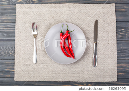 Gray plate with chilli red pepper on , spoon and knife Gray plate with chilli red pepper on , spoon and knife 66263095