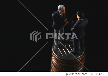 Miniature dolls shaking hands on a black background 66263735