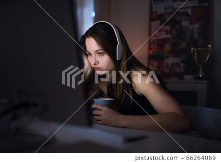 Bored young girl with computer sitting indoors, online chatting concept. Bored young girl with computer sitting indoors, online chatting concept. 66264069