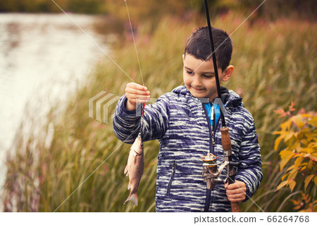 Cute boy catches fish on a summer lake. Cute boy catches fish on a summer lake. 66264768