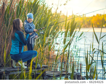 Cute boy with mom catches fish on a summer lake. Cute boy with mom catches fish on a summer lake. 66264826