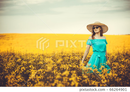 Young woman standing on the rape field with sunrise on the background 66264901