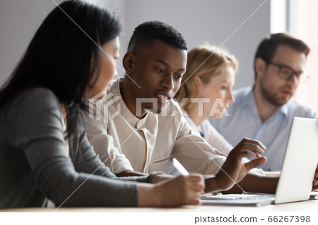 Multiethnic colleagues seated in coworking room discuss new corporate app Multiethnic colleagues seated in coworking room discuss new corporate app 66267398