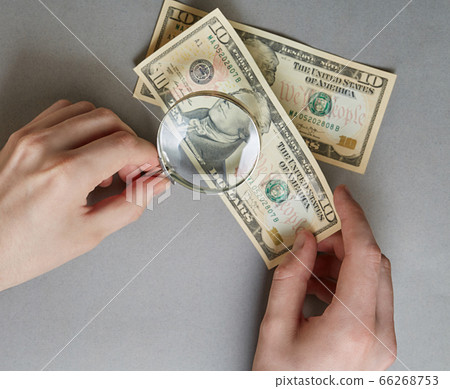 finance. hand with a magnifying glass over paper 66268753