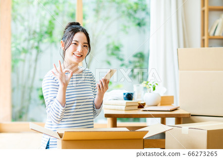 A young woman operating a smartphone to search for a moving company 66273265