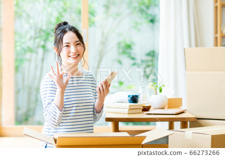 A young woman operating a smartphone to search for a moving company 66273266