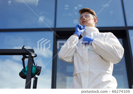 Young Worker Putting On Protective Suit Outdoors 66274109