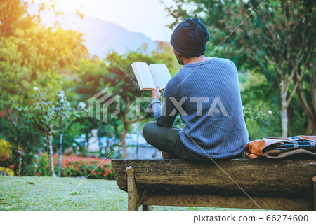 The young man travels nature on the mountain, is sitting and relaxing, reading a book The young man travels nature on the mountain, is sitting and relaxing, reading a book 66274600
