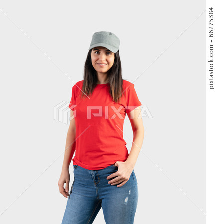 Young girl wearing blank red t-shirt, cap and blue jeans. Grey wall background Young girl wearing blank red t-shirt, cap and blue jeans. Grey wall background 66275384