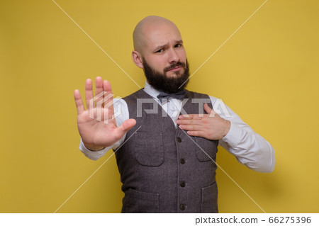 Mature man making stop sign on yellow studio wall. Mature man making stop sign on yellow studio wall. 66275396